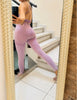 Frau im lila Fitness-Set mit Leggings und Rückenausschnitt – stylisch und sportlich.